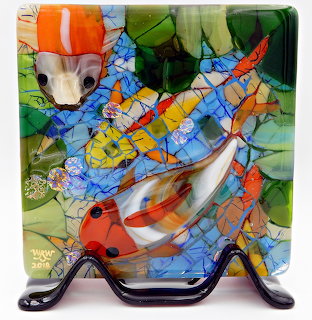 Colorful stained glass mosaic showing koi fish with water lilies in vivid orange, blue, yellow and green tones