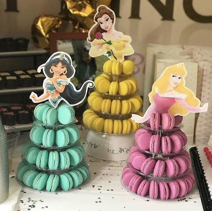 Three stacked macaron towers with Disney princess toppers in teal, yellow, and pink colors