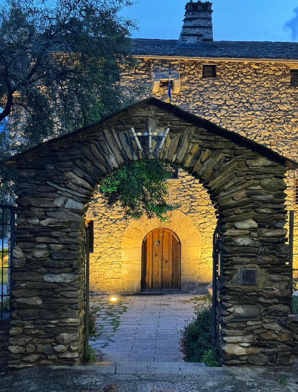 Stone archway gate with wooden door lit at dusk in Andorra la Vella