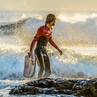 Surfer on Rocky Shore
