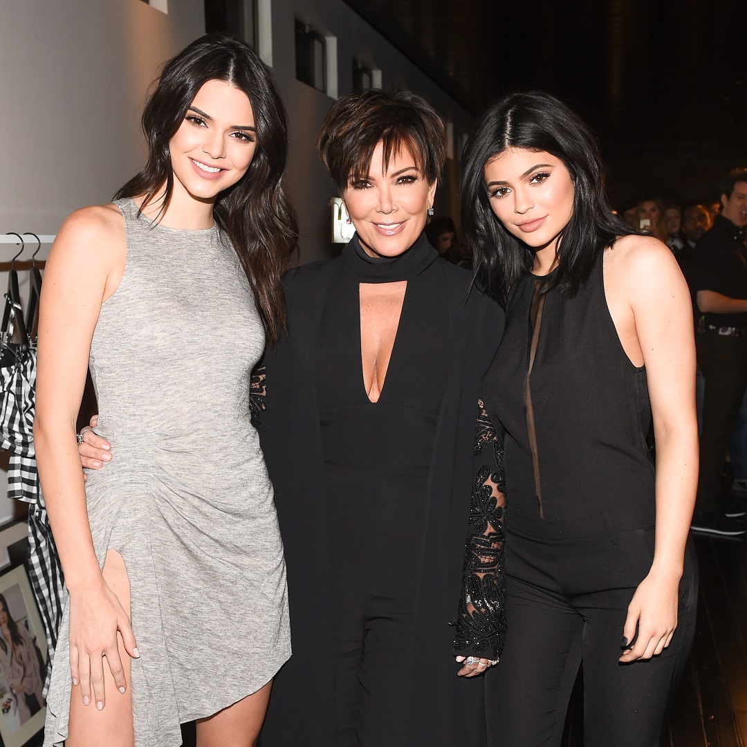 Three women posing together indoors in gray and black outfits