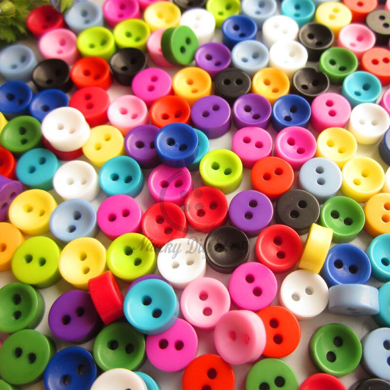 Many small colorful plastic sewing buttons with two and four holes scattered on a surface