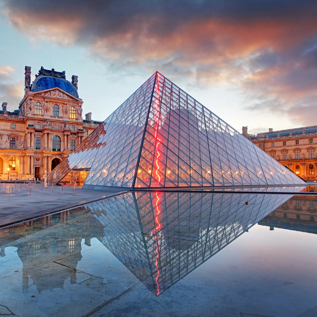Louvre Pyramid in Paris reflected in a still pool at dusk