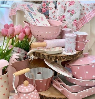 Collection of pink polka dot kitchenware with tulips and floral fabric on a wooden display