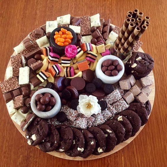 Round platter overflowing with assorted chocolates, cookies, brownies, candies, and wafer rolls