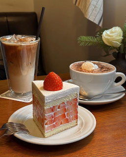 Strawberry shortcake slice with iced latte and cappuccino on a wooden table in a cafe