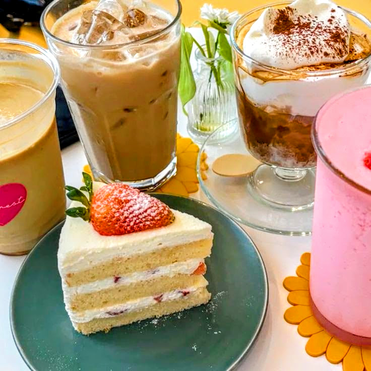 Strawberry layer cake with iced coffee, a whipped dessert, and a pink drink on a bright table
