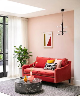 Modern living room with coral sofa, marble table, pink walls, and large glass door