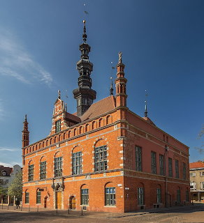 Red brick Old Town Hall in Gdansk with tall ornate spire and Gothic architectural details