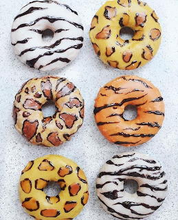 Six donuts with animal print frosting in leopard, tiger, and zebra patterns on white background