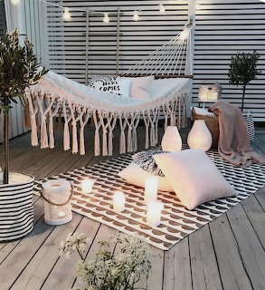 Macrame hammock on a cozy patio with pillows, lanterns, and a patterned rug