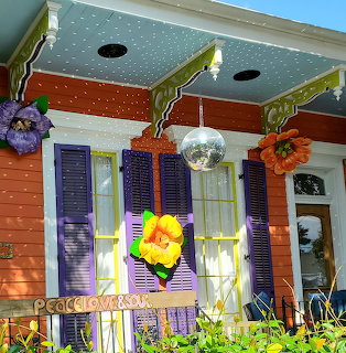 Colorful house porch with purple shutters, orange walls, flowers, and disco ball decoration