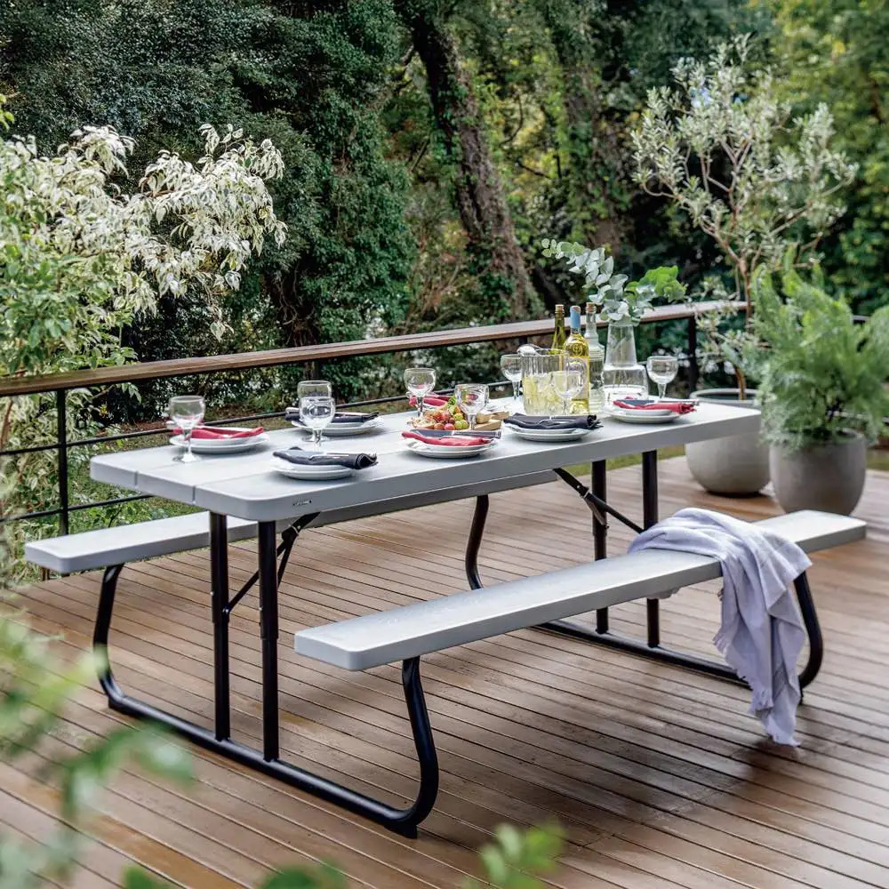 Outdoor dining table with benches on wooden deck surrounded by garden foliage