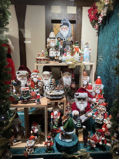 Christmas shop display with Santa figures, snowmen, and holiday ornaments on wooden shelves