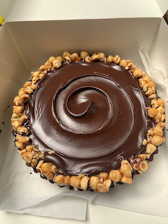 Chocolate ganache pie with swirled top and caramel popcorn border in a white box