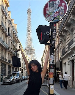 Woman in black posing on Parisian street with Eiffel Tower behind her