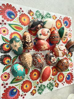 Assortment of decorated Easter eggs with folk art patterns on a colorful floral cloth