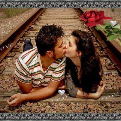 Young couple kissing while lying on railroad tracks with a red rose nearby