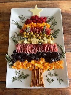 Christmas tree shaped cheese and charcuterie board with meats, fruits, vegetables arranged in colorful rows