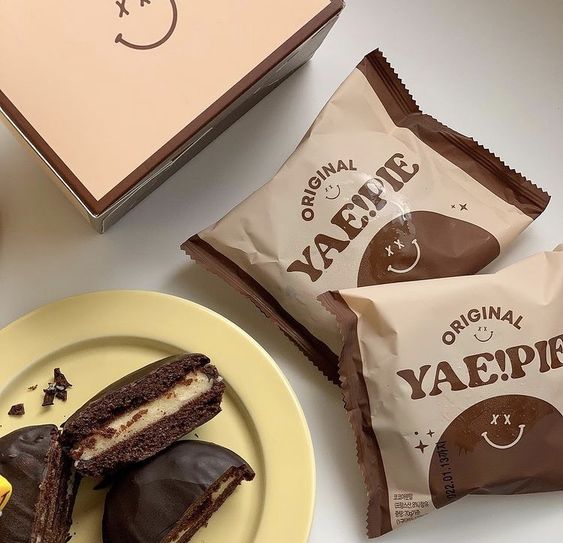 Chocolate cream pie snacks, one cut open on a yellow plate next to two wrapped pies