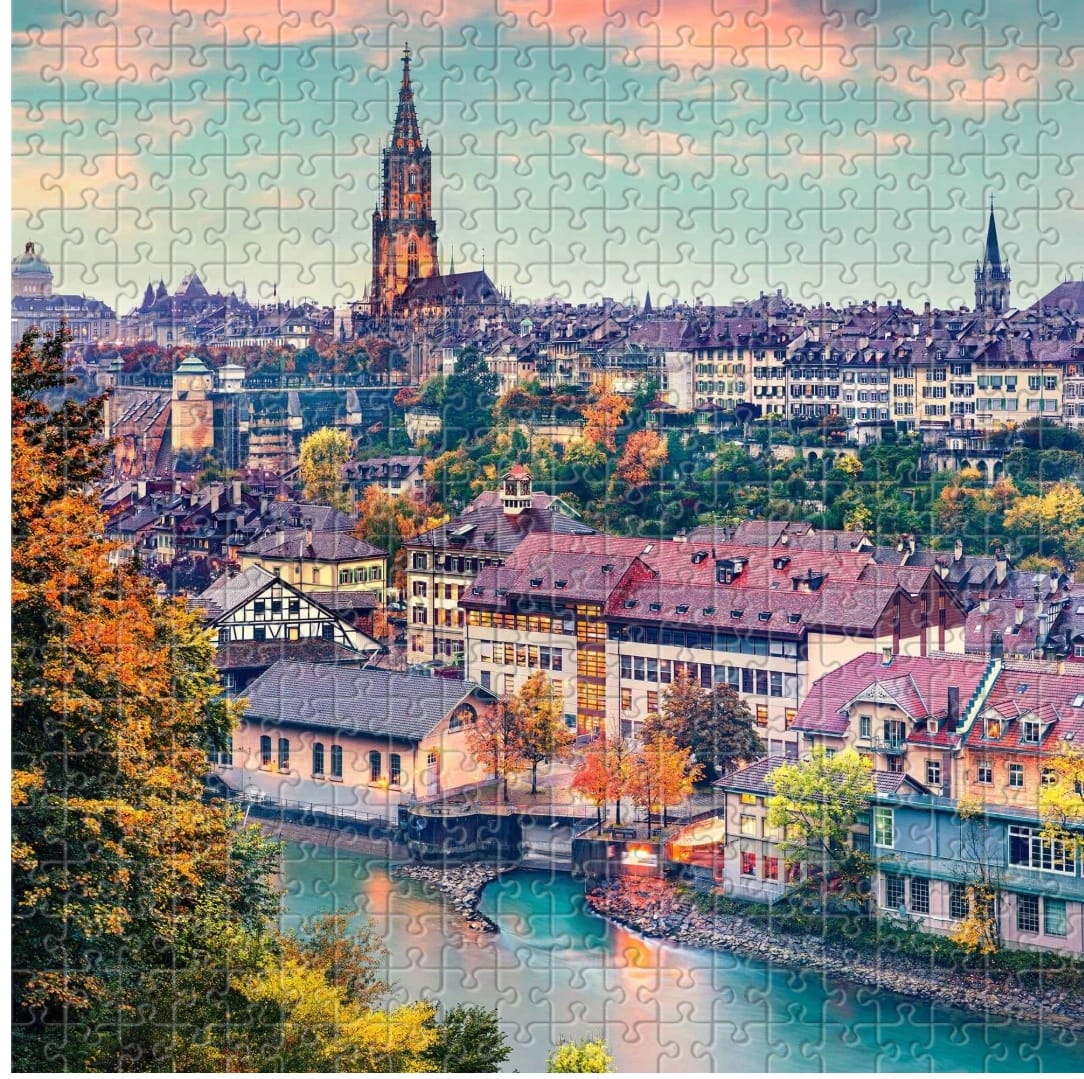 European town with church spires, autumn trees, rooftops, and a turquoise river canal