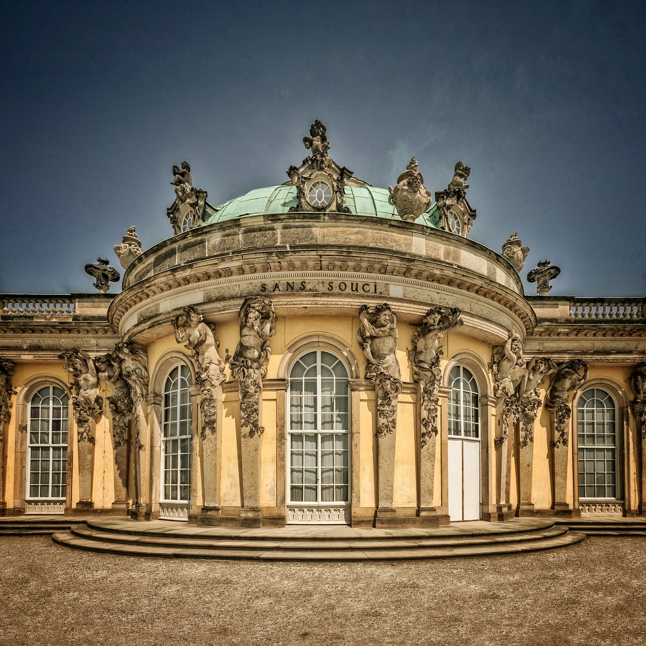 Curved yellow Rococo pavilion with columns and ornamental sculptures under dramatic cloudy sky