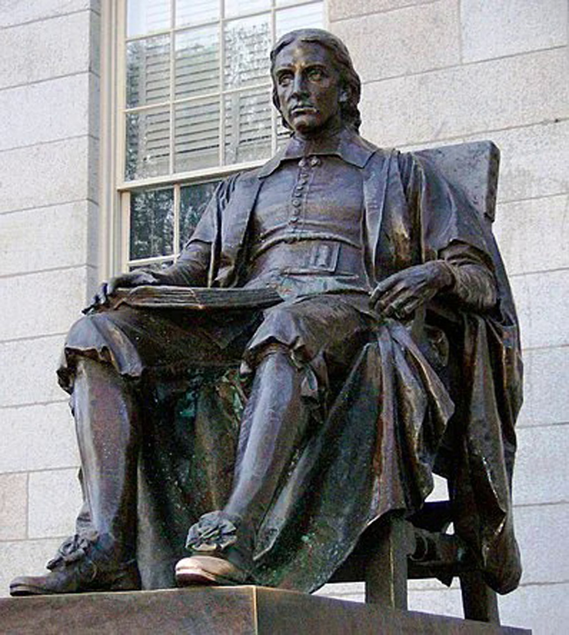 Bronze statue of seated figure in colonial dress on stone base
