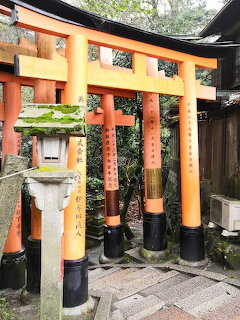 Orange torii gates at a Japanese shrine with stone lanterns and green vegetation