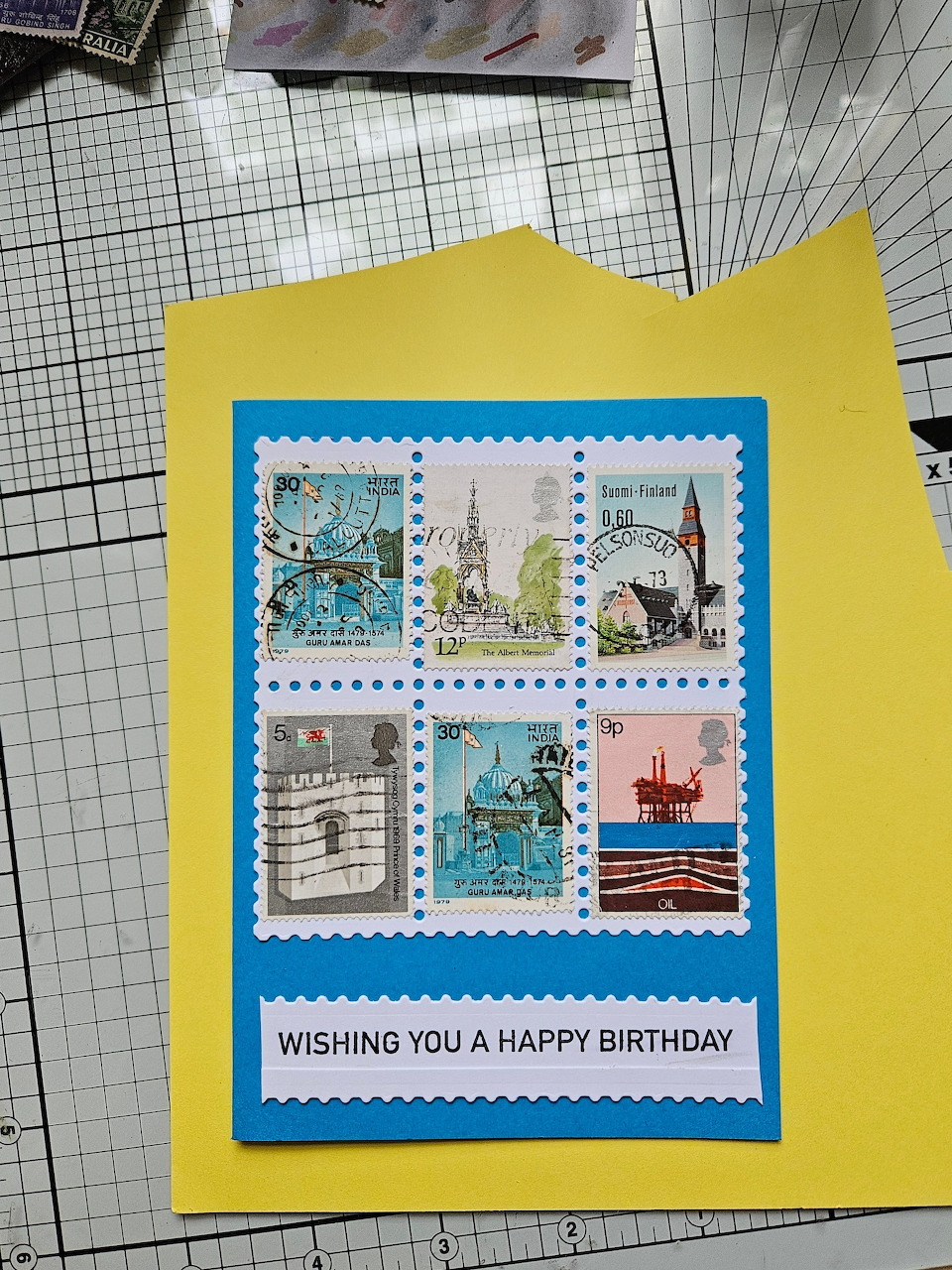 Handmade birthday card with decorative postage stamps in nautical theme on yellow envelope