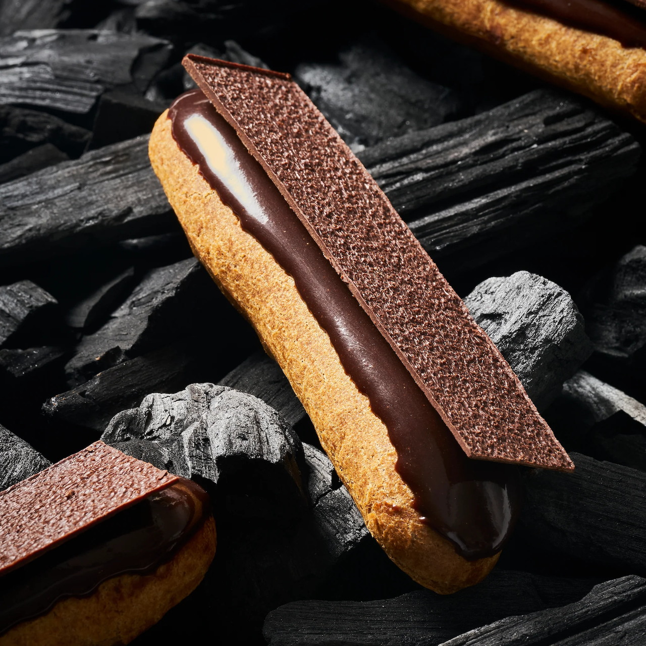 Chocolate eclair with cream filling placed on dark charcoal background