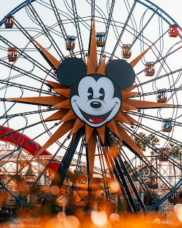 Ferris wheel with Mickey Mouse face center in orange and gray at amusement park