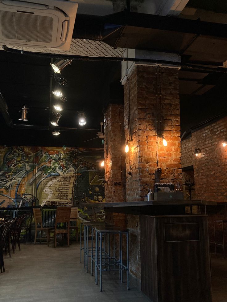 Dimly lit coffee shop with brick walls, hanging lights, and wooden bar with stools