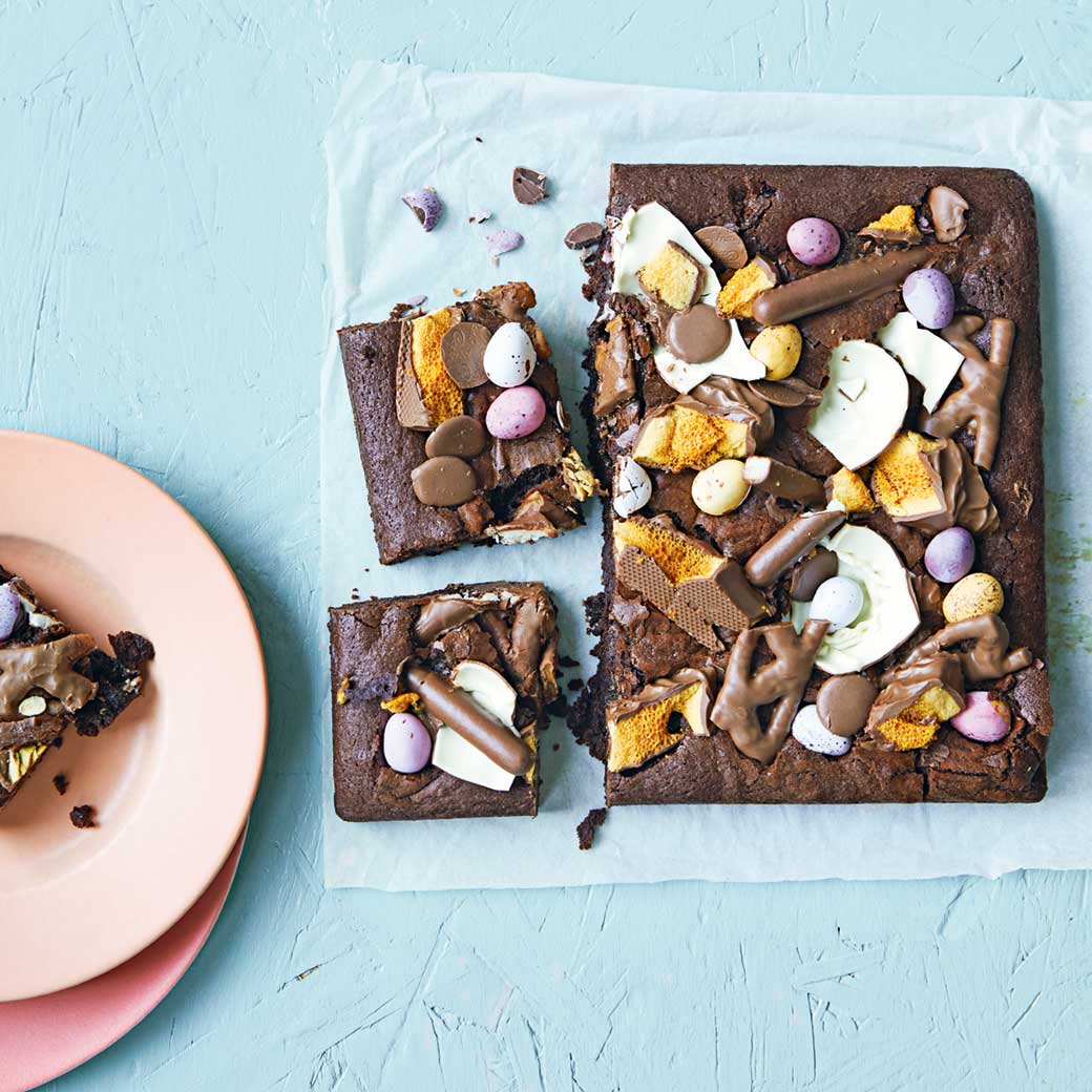 Chocolate brownies with marshmallows and candy toppings on blue surface