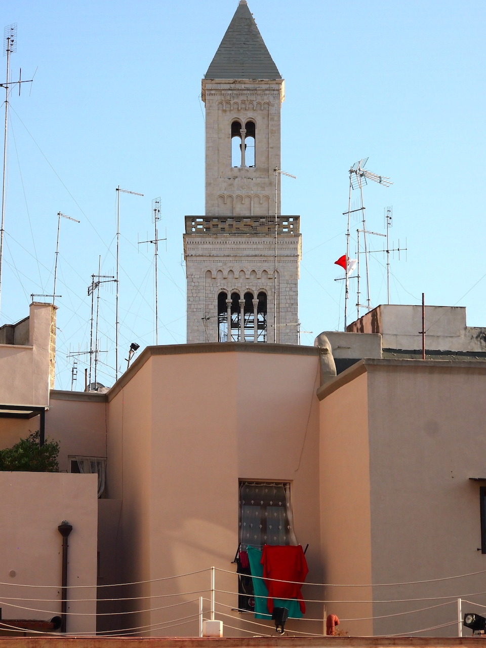 Bell tower above peach-colored buildings in Bari, Italy