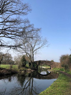 Stone arch bridge crossing a tranquil canal with tree reflections in winter