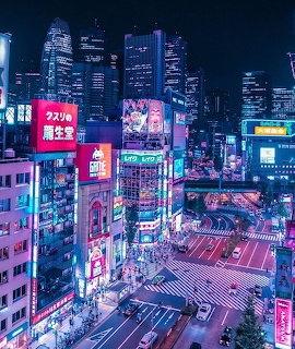 Aerial view of busy Tokyo intersection at night with bright neon signs and colorful billboards