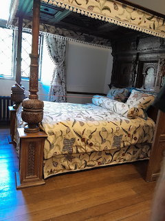 Historic bedroom with a carved four-poster bed and patterned bedspread