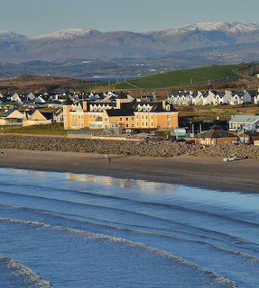 Rossnowlagh beach with village houses and snow-covered mountains reflecting in water