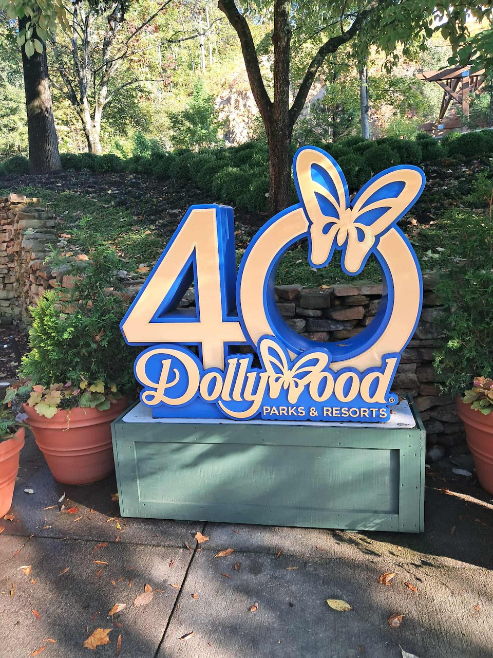 Dollywood Parks & Resorts 40th anniversary sign with butterfly, surrounded by greenery and potted plants