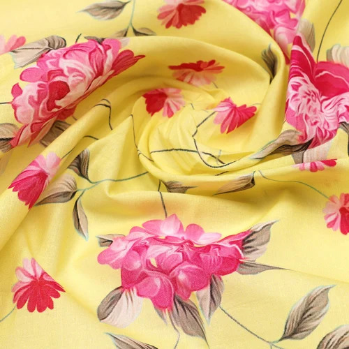 Yellow fabric with pink floral print, draped with soft folds showing repeating flower pattern