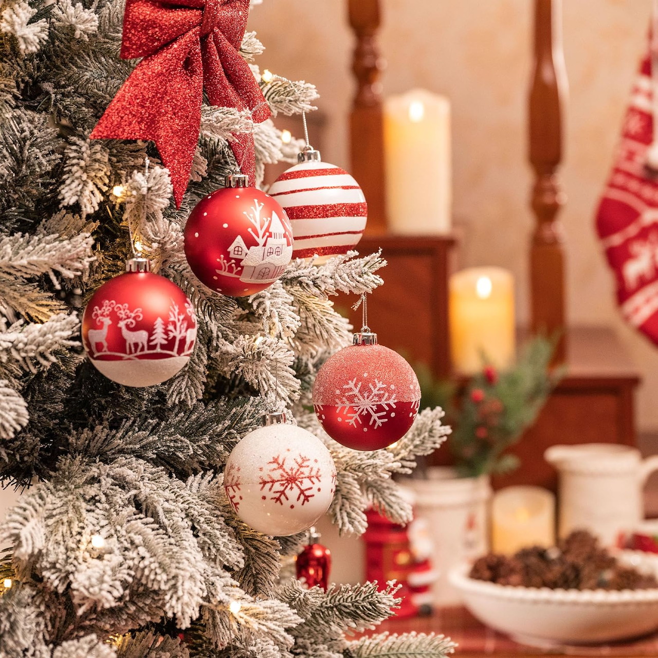 Red and white Christmas ornaments on a frosted evergreen tree with a red bow and warm candles in the background