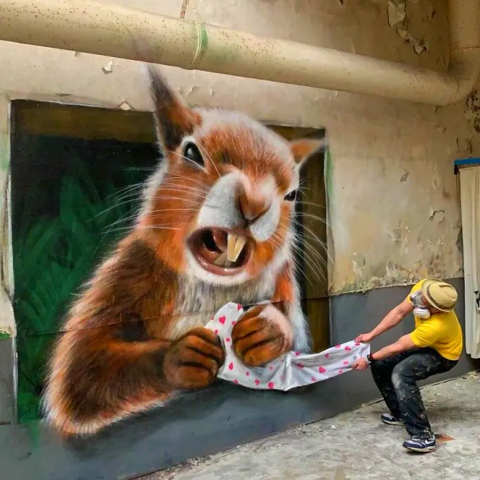 Person posing with 3D street art mural of angry squirrel appearing to grab their shirt