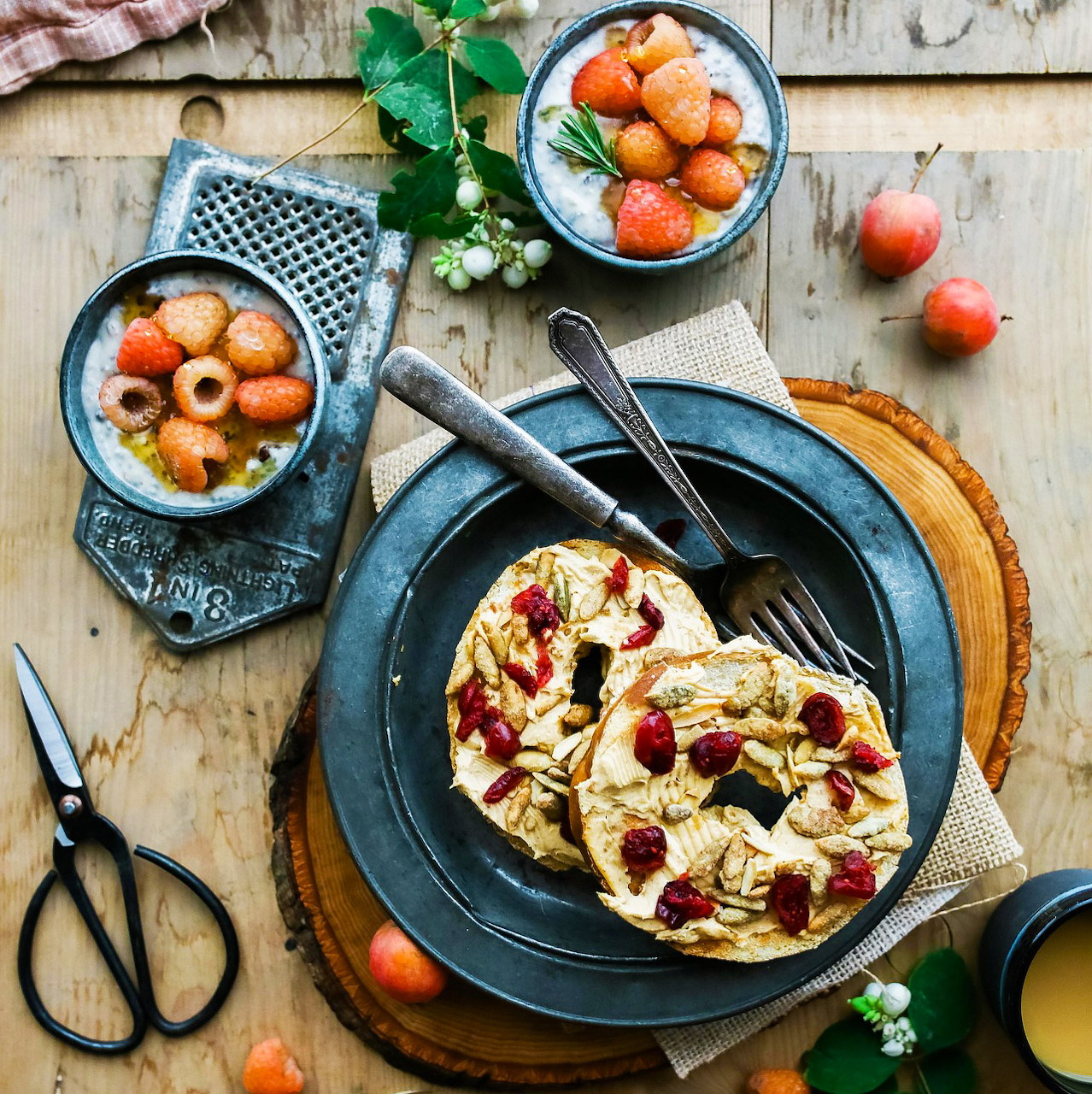 Flatbread with cream cheese, almonds and cranberries on dark plate with strawberries and mint on wooden table