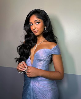 Young woman in a lavender off-shoulder pleated gown with long black wavy hair and silver jewelry