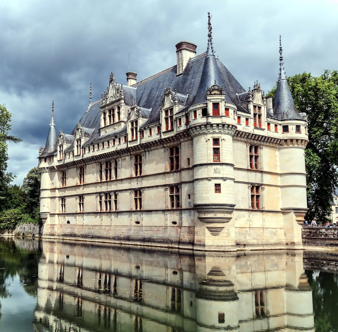French château with pointed roofs reflected in a still moat