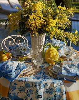 Yellow mimosa bouquet with blue and white china and fruit on decorated table