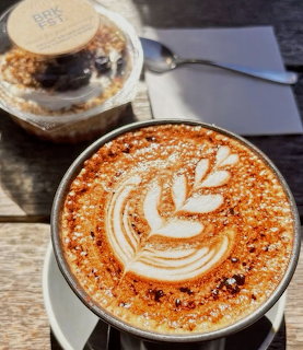 Cappuccino with leaf latte art and alfajor cookie on outdoor café table