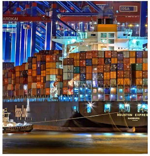 Containership loaded with cargo containers at a brightly lit port at night