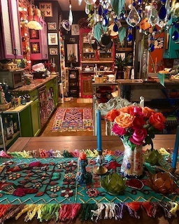 Colorful bohemian interior with patterned rugs, hanging ornaments, lamps, and flowers on a table