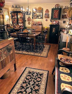 Vintage primitive kitchen with wooden table, Windsor chairs, oriental rug, and decorative plates on walls
